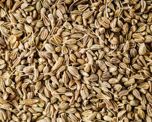 aromatic dry anise seeds on a dark black stone background.